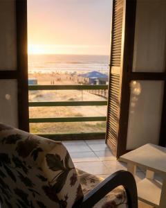 a room with a chair and a view of a beach at Hotel D'Italia in Arroio do Sal