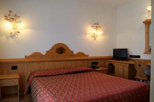 a bedroom with a bed with a red bedspread and a tv at Hotel Milano in Asiago