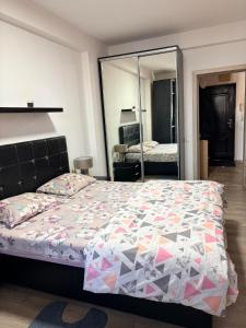 a bedroom with a large bed and a mirror at Apatement de luxe in Roşu