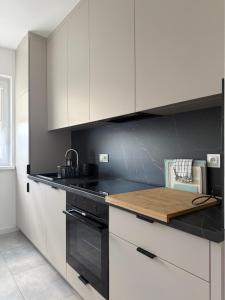 a kitchen with white cabinets and a wooden counter top at Apartamenty u Rybaka in Stężyca