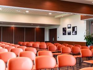 an empty conference room with orange chairs in it at Mercure Bayeux Omaha Beach in Port-en-Bessin-Huppain +154 photos