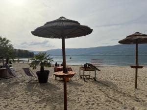 a beach with tables and umbrellas on the sand at Studio yvonand in Yvonand