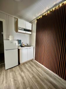 a kitchen with a white refrigerator and a wooden wall at OffGrid Retreat Rtanj in Boljevac