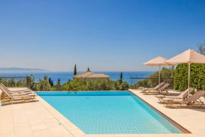 a swimming pool with chairs and umbrellas at Villa Mihas in Vlachata