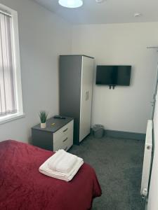ein Schlafzimmer mit Bett, Kommode und Fernseher in der Unterkunft PLUS Properties Dike 3 Ensuite in Stoke on Trent