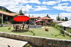 a table and chairs with an umbrella in a yard at Los Portales de Yungar Ecolodge Huaraz in Carhuaz