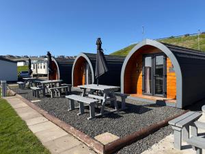 a group of picnic tables in front of a cabin at Marina Bay Pods in Aberdeen