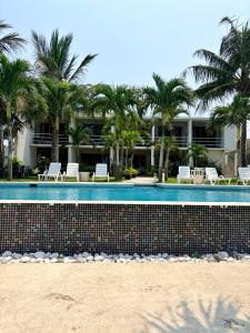 a resort swimming pool with chairs and palm trees at Hotel Lunazul In Costa Esmeralda in La Vigueta