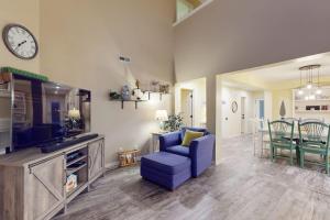 a living room with a blue chair and a tv at Sea Colony - 56182 Pine Branch Way in Bethany Beach