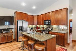 a kitchen with wooden cabinets and a kitchen island with bar stools at 4BR Townhome Near Canyon Lodge & Lakes Basin in Mammoth Lakes