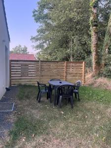 a table and chairs in a yard with a fence at Cottage with garden in La Roche-sur-Yon