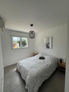 a white bedroom with a bed and a window at Cottage with garden in La Roche-sur-Yon