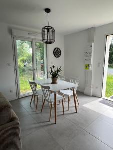 a dining room with a white table and chairs at Cottage with garden in La Roche-sur-Yon