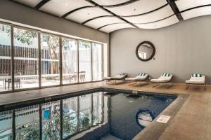 a swimming pool with chairs and a mirror in a building at Holiday Inn Guadalajara Patria-Universidad by IHG in Guadalajara