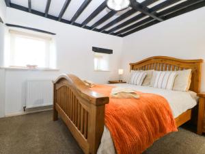 a bedroom with a wooden bed with an orange blanket at Farm Cottage in Cemaes Bay