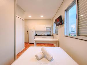 a small kitchen with a white refrigerator and a window at Prado Premium Lofts e Kitnets com Ar-Condicionado e TV Smart in Belo Horizonte +19 photos