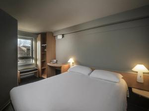 a bedroom with a large white bed with two pillows at ibis Carcassonne Centre - La Cité in Carcassonne