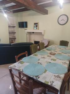a dining room with a table with chairs and a clock at Chez Pépé in Limalonges
