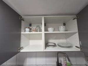 a white cabinet with plates and dishes on it at Nektarios Apartments in Kernen