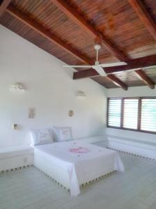 a white room with a bed with a wooden ceiling at BeachCasaDonPepe in Barra de Potosi
