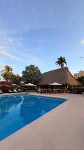 a large swimming pool with a restaurant with a thatched roof at BeachCasaDonPepe in Barra de Potosi