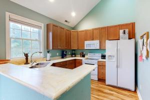 a kitchen with a white refrigerator and wooden cabinets at Bear Trap Dunes - 91 Willow Oak in Ocean View
