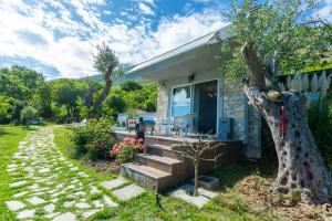 a small house with a porch and a tree at Nature Oasis Kravari - Private Pool & Jacuzzi in Stegvaši