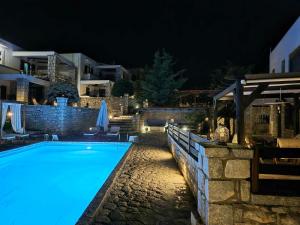 a swimming pool lit up at night at Malvazios Villas Panorama Pool Villa in Gythio
