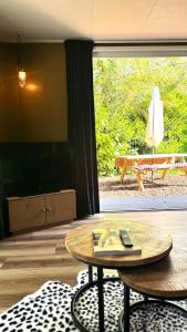 a living room with a table and a large window at Panterhuis Leo l Tiny House l Buitenbad, airco, speeltuin, bostuin in Epe