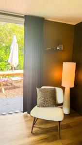 a living room with a chair and a lamp at Panterhuis Leo l Tiny House l Buitenbad, airco, speeltuin, bostuin in Epe