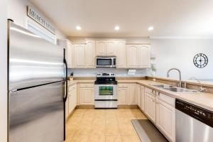 a kitchen with white cabinets and a stainless steel refrigerator at The Tides -- 20007 Sandy Bottom # 4202 in Rehoboth Beach