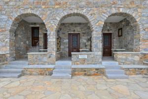 a stone building with three arched windows and stone stairs at Moutsouna Seaside in Moutsoúna