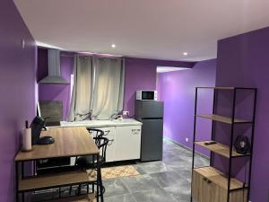 a kitchen with purple walls and a table and a refrigerator at Comme à la maison in Villiers-en-Bière +3 photos