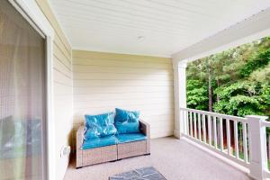 a porch with a blue chair on a balcony at The Peninsula --- 22308 Dune Cir 74 in Millsboro