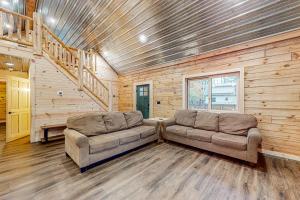 a living room with two couches and a wooden wall at Black Bear Cabin in Tomahawk