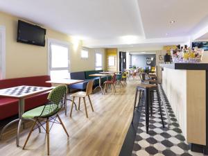 a restaurant with tables and chairs and a bar at ibis Rochefort in Rochefort