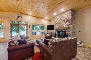 a living room with two couches and a stone fireplace at Pair-a-Docks Landing in Minocqua