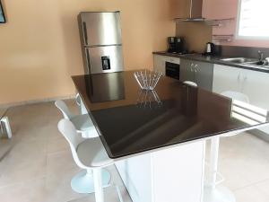 a kitchen with a black counter top with white chairs at Ti Kaz en Nou' in Pointe-Noire