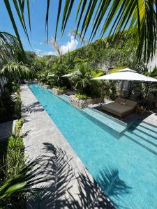 a swimming pool with umbrellas and palm trees at Ontico Urban Design Hotel in Mérida