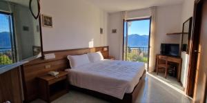 ein Schlafzimmer mit einem Bett und einem großen Fenster in der Unterkunft Hotel Montegrino Lakeview in Montegrino Valtravaglia