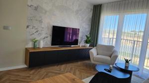 a living room with a television and a chair at Jeziorna Premium Apartment in Siewierz +8 photos