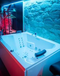 a white bath tub with a stone wall at La Cachette Secrète - Maison romantique avec Balnéo et Sauna Privatif à Caen en Normandie in Caen