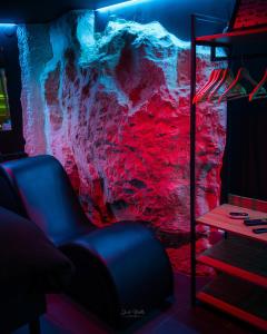 a room with a blue chair in front of a rock wall at La Cachette Secrète - Maison romantique avec Balnéo et Sauna Privatif à Caen en Normandie in Caen