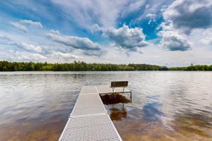 a bench sitting on a dock in the middle of a lake at Pickerel Point Home in Saint Germain