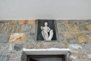 a statue of a man on a stone wall at Moutsouna Seaside in Moutsoúna