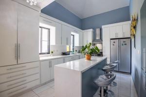 a kitchen with white cabinets and blue walls at Private Pool Villa - BBQ - Washer in Sosúa