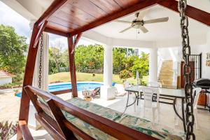 a swing in a porch with a table and a pool at Private Pool Villa - BBQ - Washer in Sosúa
