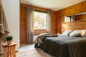 a bedroom with wooden walls and a bed with a window at Rukan Talvihovi in Ruka