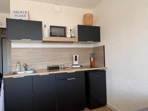 a kitchen with black cabinets and a microwave at Studio calais la plage in Calais +7 photos