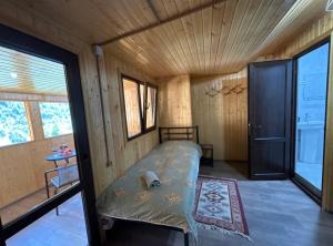 a small bedroom with a bed in a wooden room at SAOTI Guest house in Shatili